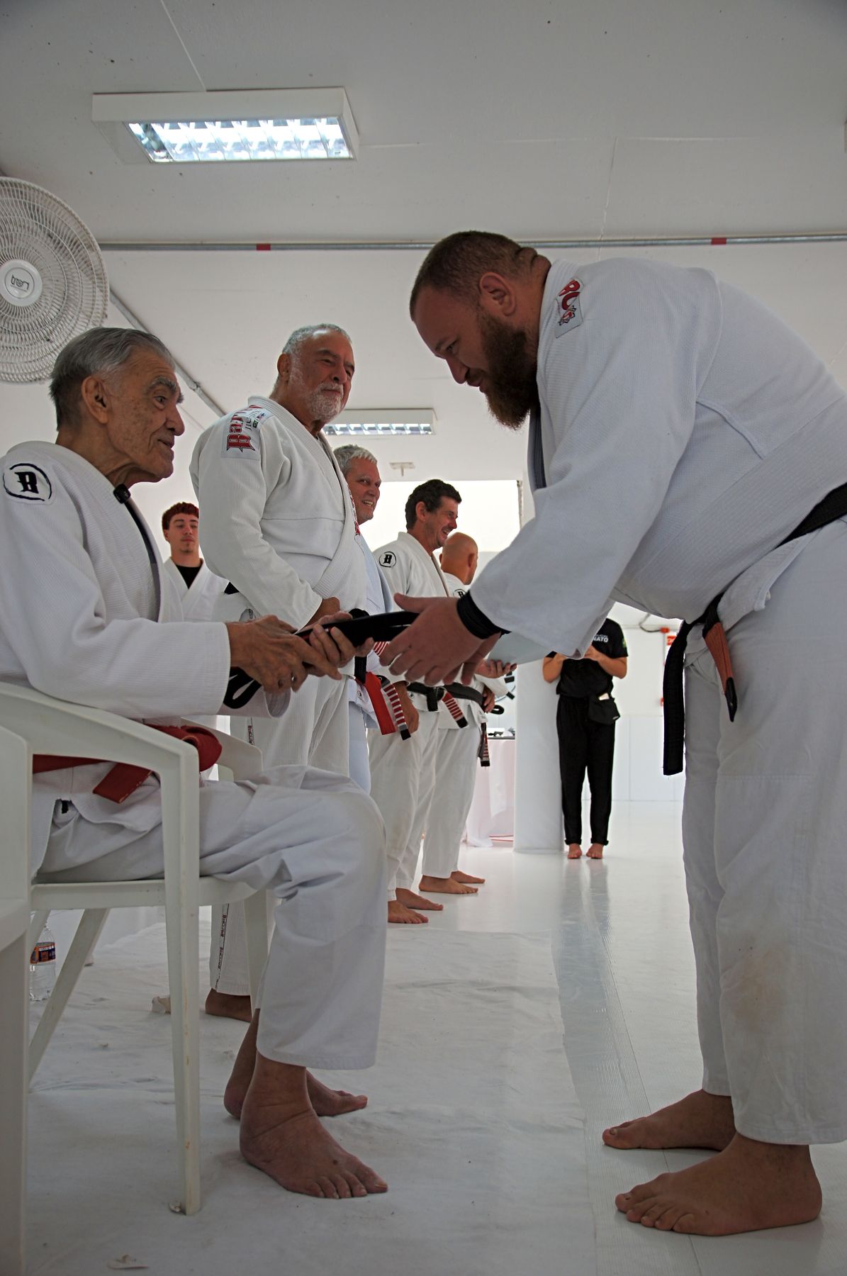 Mestre entregando a faixa preta na graduação da Barreto